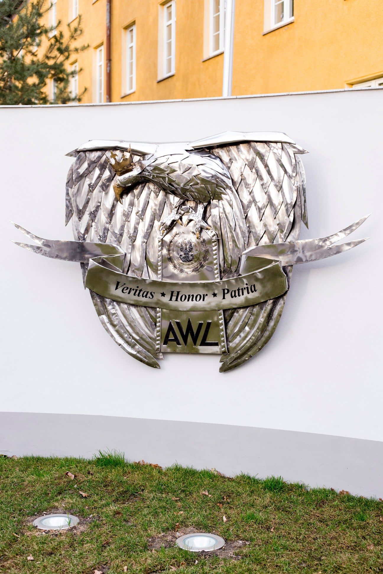 The Military University of Land Forces emblem featuring an eagle with spread wings, displaying the motto 'Veritas Honor Patria' and 'AWL' acronym on a white wall.
