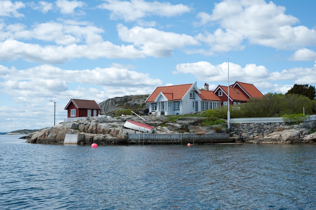 Norwegian coastal houses with red and white timber construction on rocky shoreline.