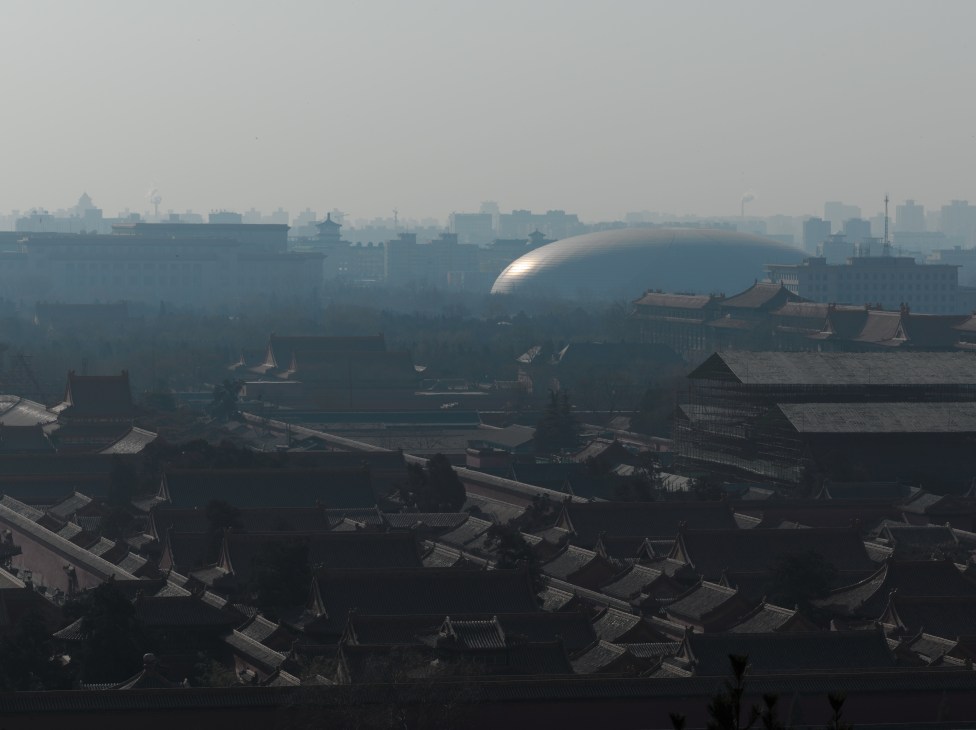 Paul Andreu's National Centre for the Performing Arts, a white dome structure, rises above traditional Forbidden City rooftops in polluted Beijing.
