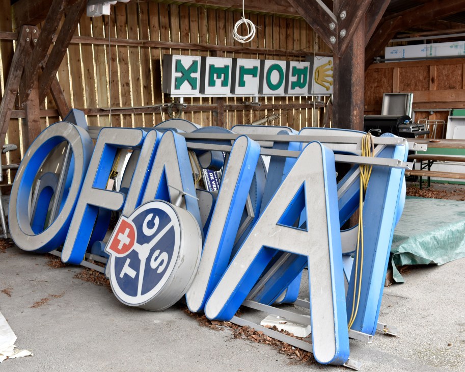 Large dimensional letters spelling OFNAV stored in a workshop yard with other decommissioned signage