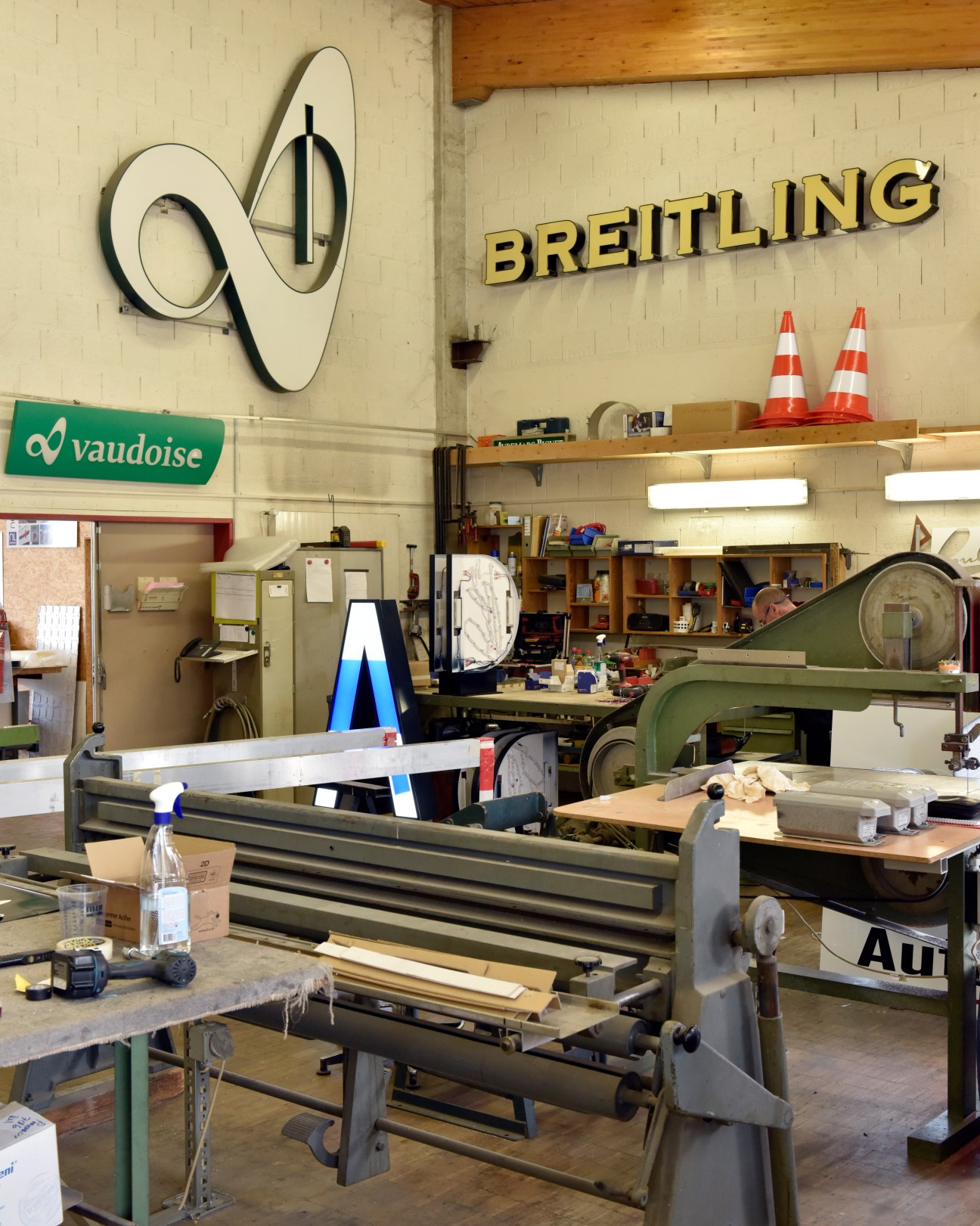 Traditional sign-making workshop with metalworking equipment and industrial machinery at Néon-Lumière