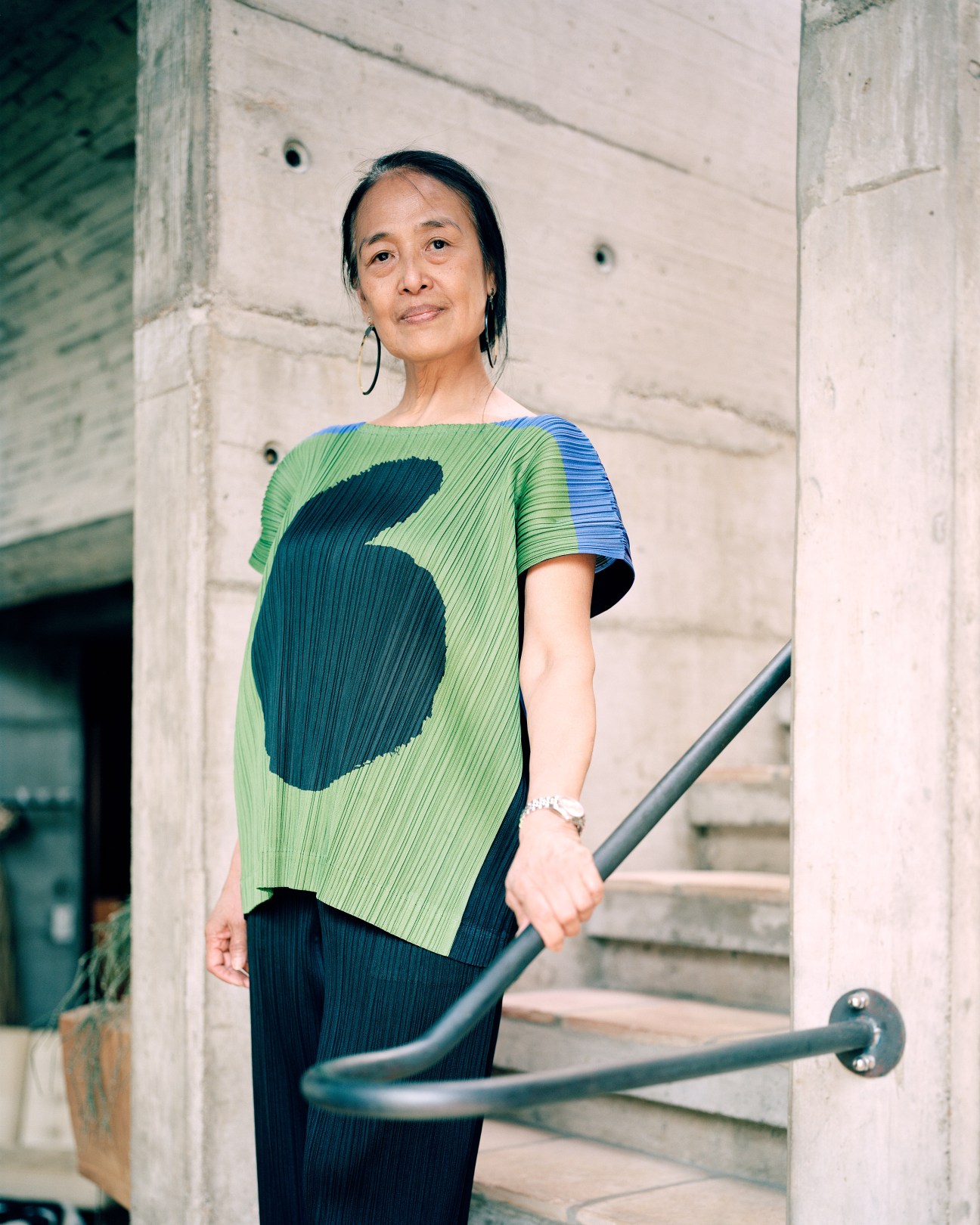 Menchu, Eduard Neuenschwander's second wife, standing in a modernist concrete hallway wearing a blue and green striped top.