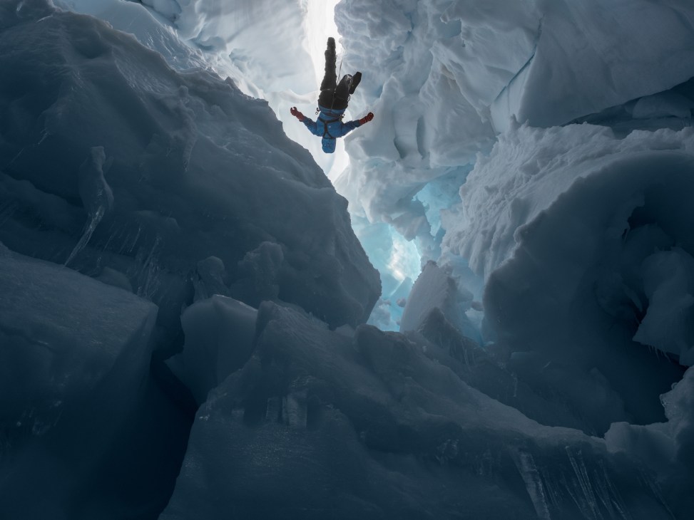 Researcher suspended in a deep ice crevasse on the Juneau Icefield in Alaska.