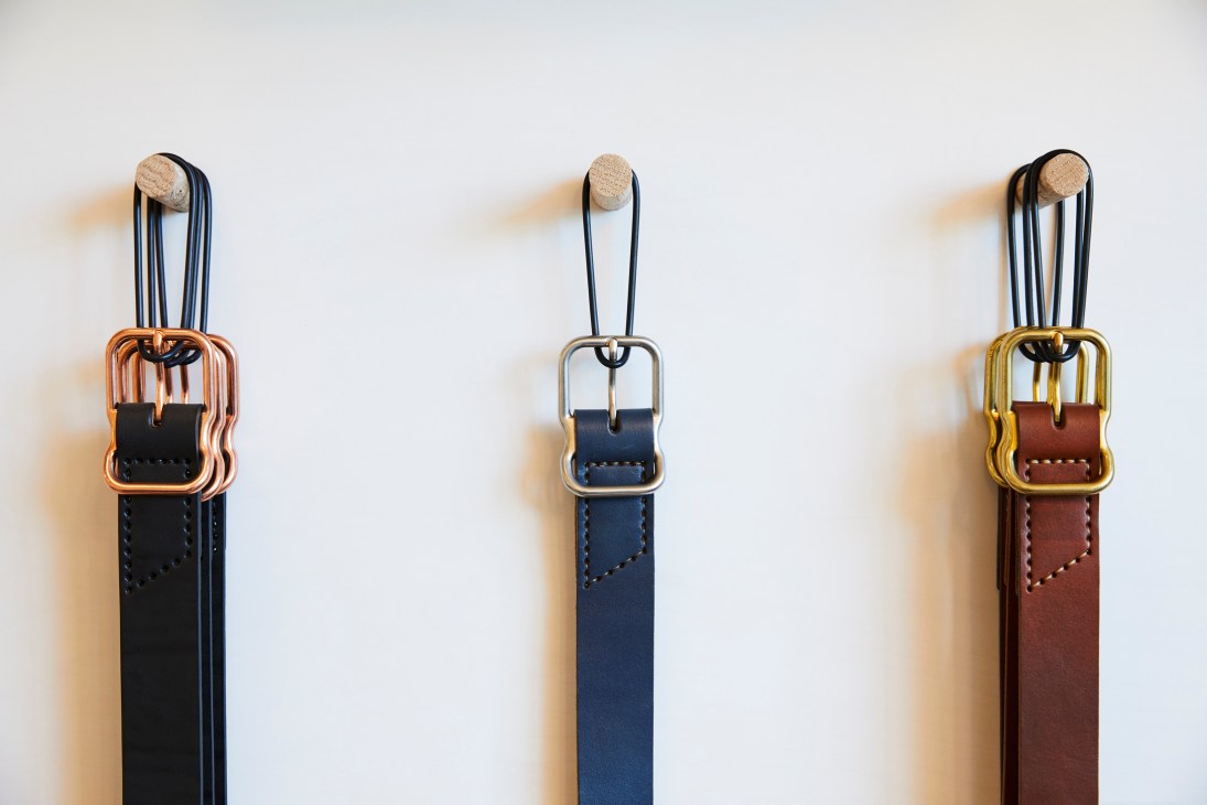 Three leather belts with wooden buckles displayed in black, navy, and brown colors.