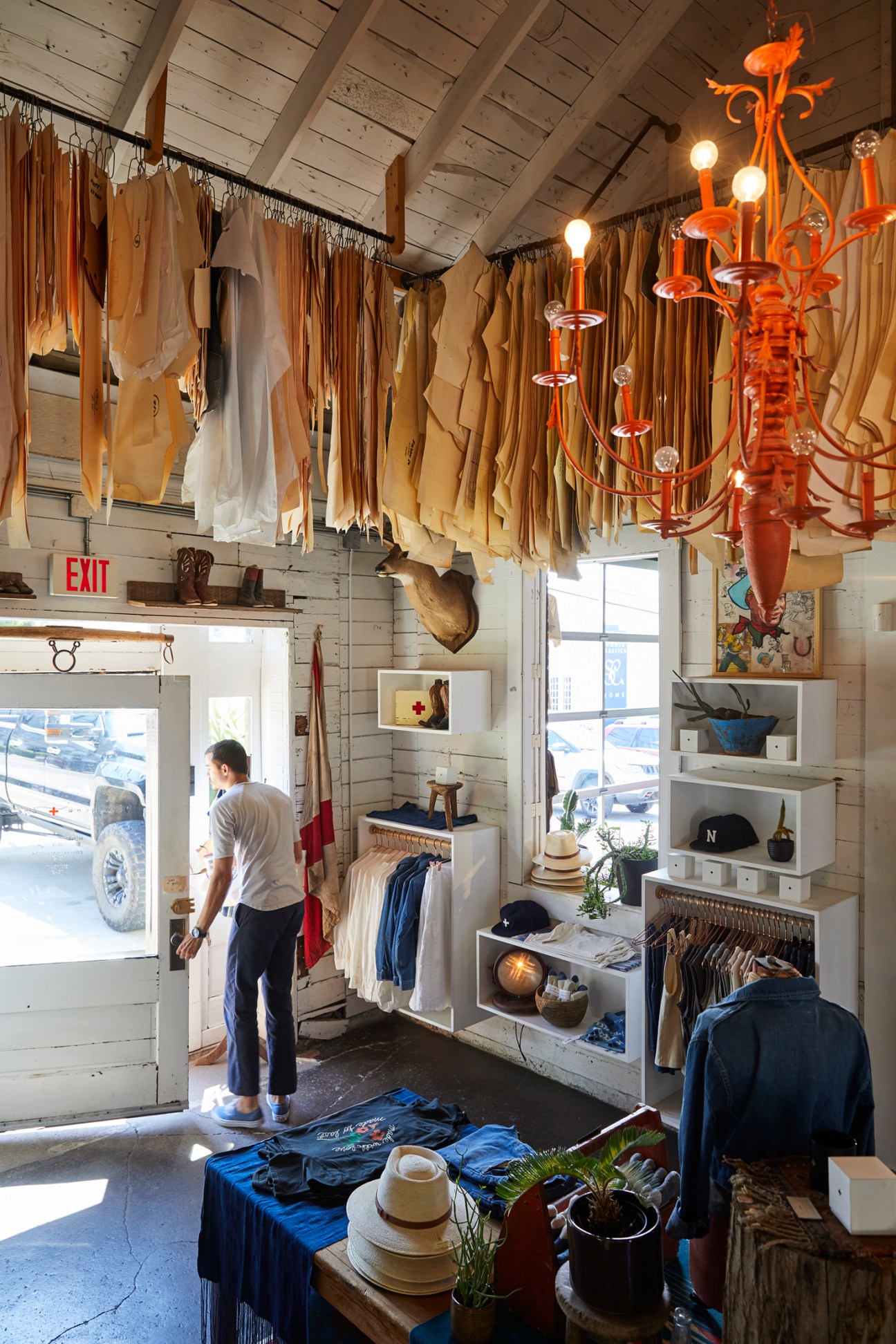Interior of Imogene + Willie shop displaying hanging fabrics and clothing with an orange chandelier.