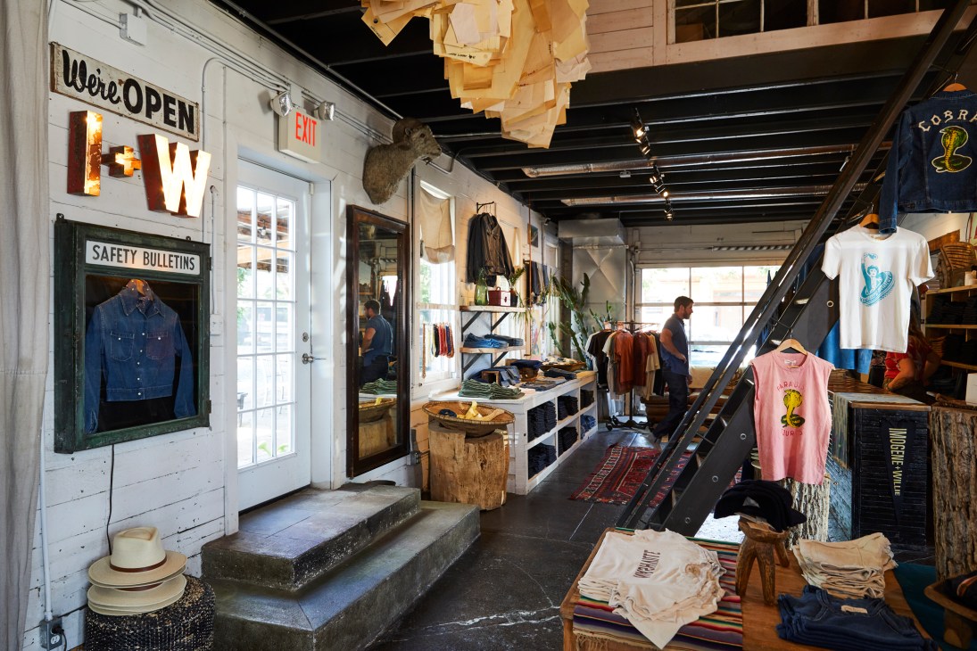 Interior of Imogene + Willie shop showing clothing displays, vintage signage, and industrial ceiling details.