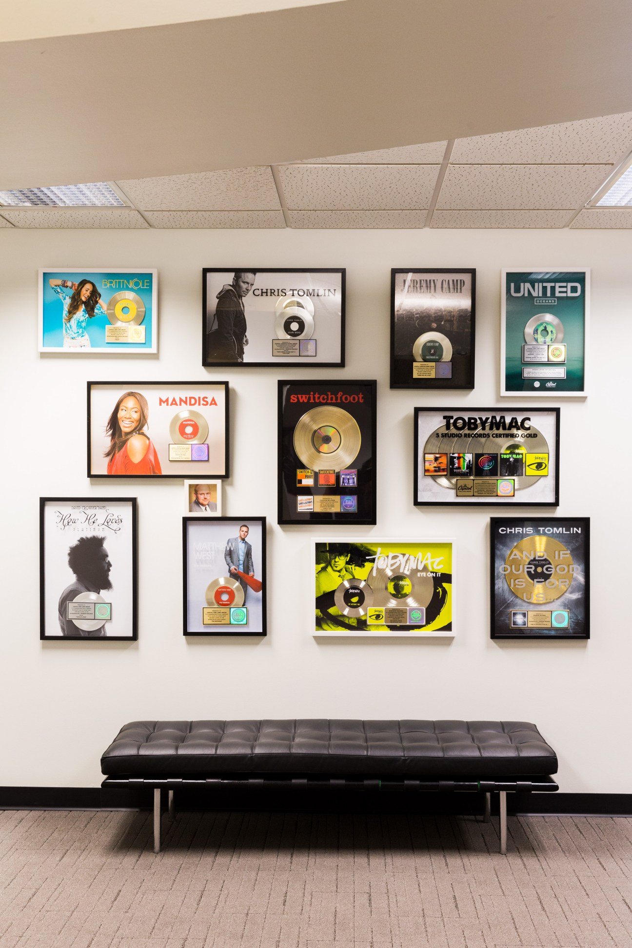 Gold and platinum certification discs displayed on a wall above a black bench at CCMG headquarters.