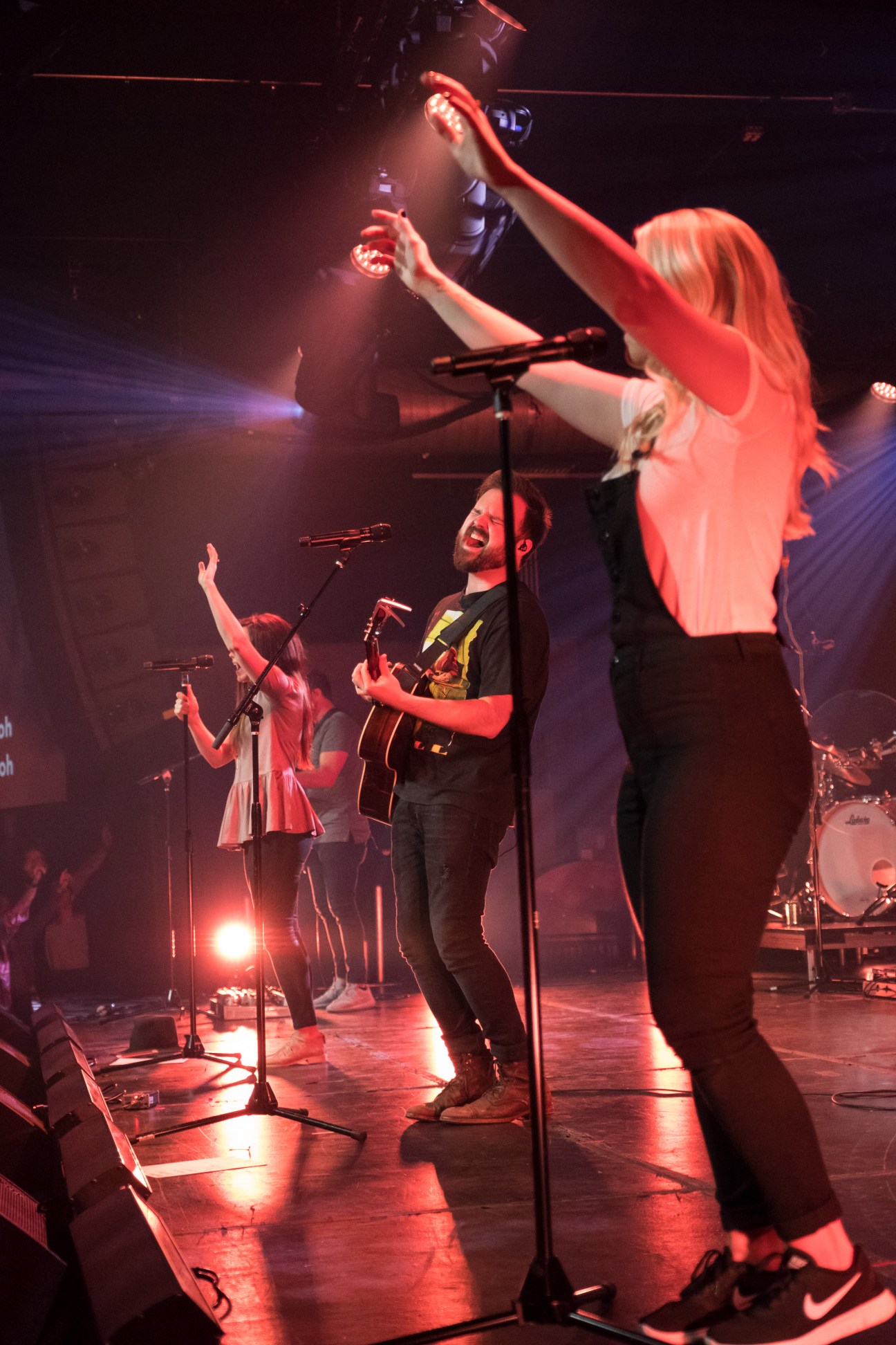 Kari Jobe and Cody Carnes performing worship music on stage with red lighting at The Belonging Co in Nashville.