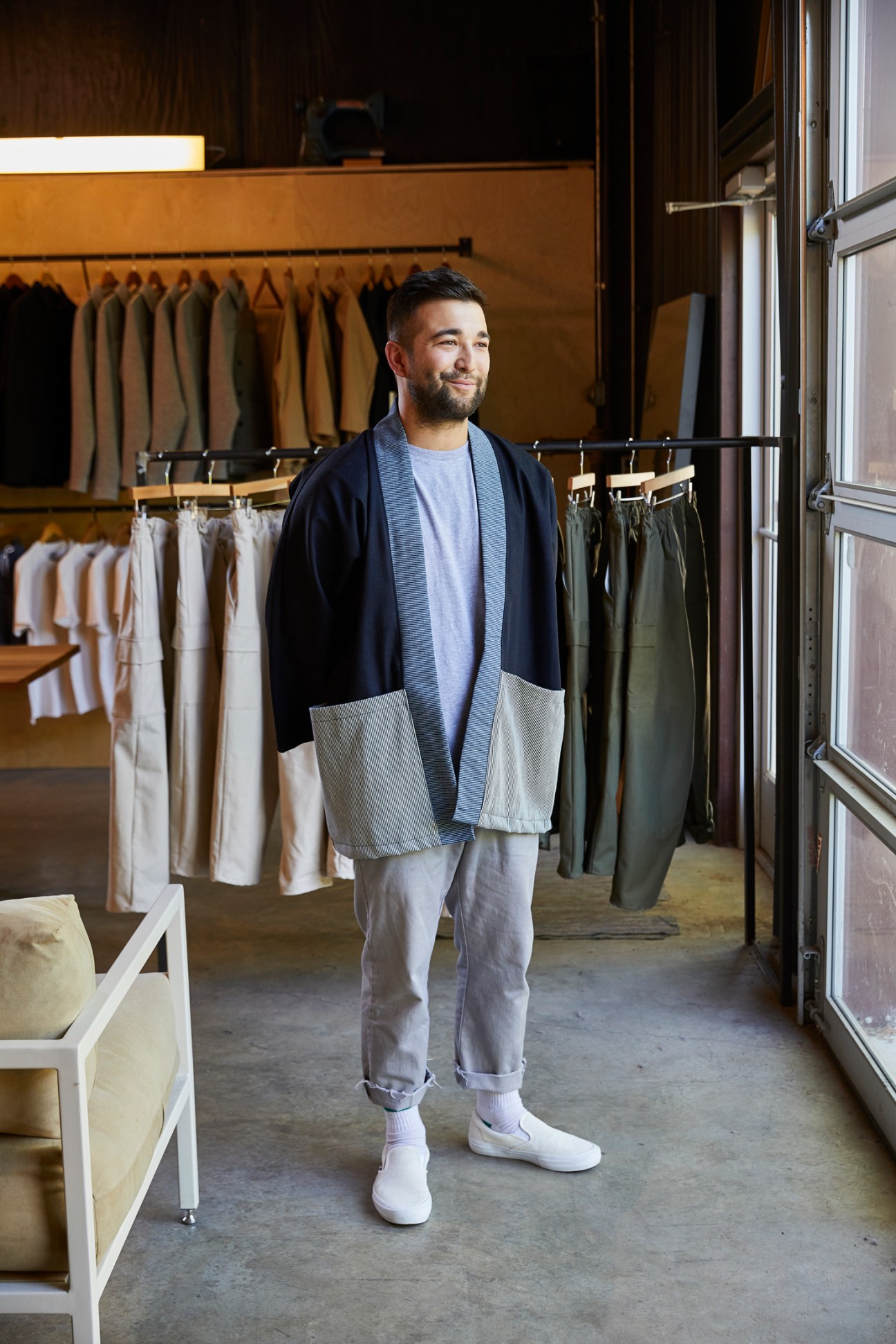 Ethan Summers, designer and owner of Oil + Lumber, stands in his showroom surrounded by clothing racks.