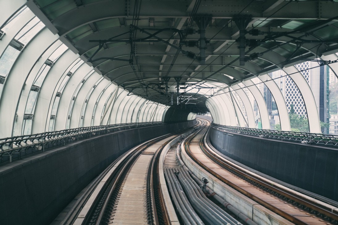 Hong Kong MTR train tunnel with curved tracks extending into the distance through a modern enclosed station.