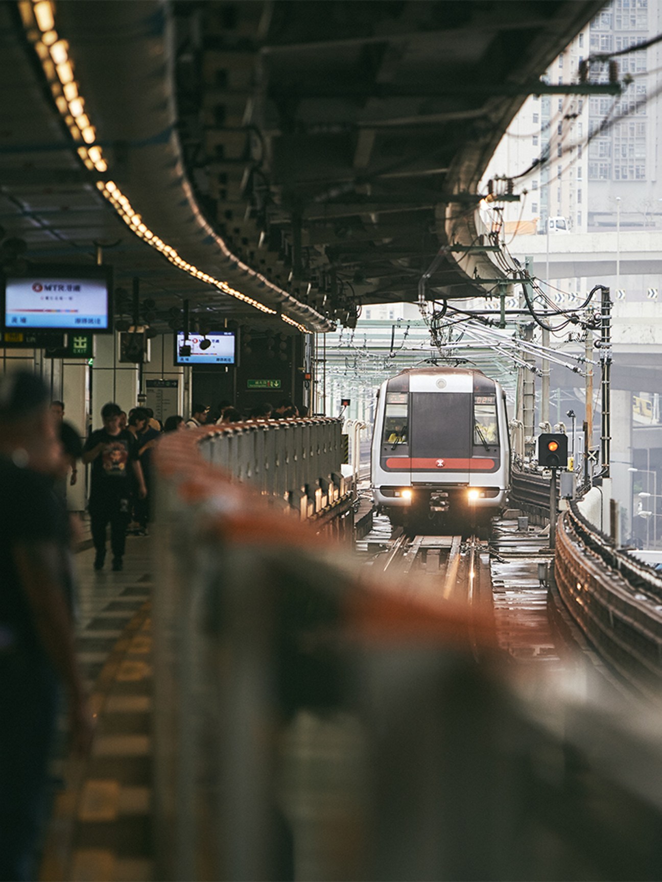 Passengers wait on a platform as a Mass Transit Railway train arrives at a Hong Kong MTR station.
