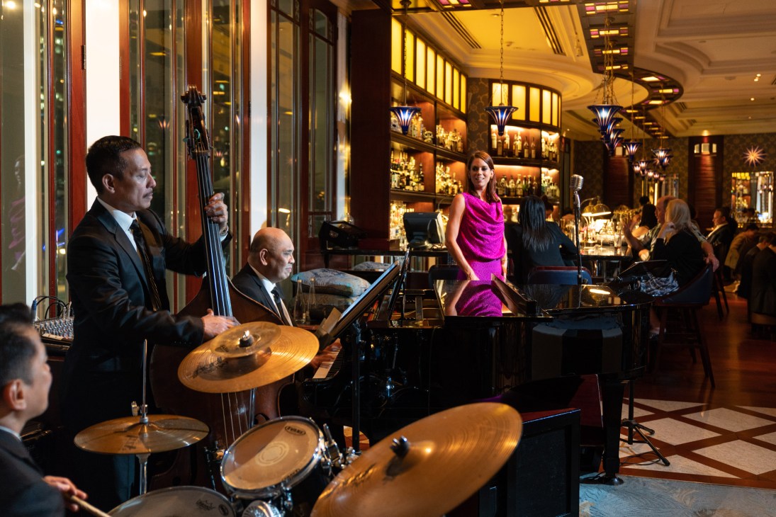 Pianist performing at grand piano in elegant Lobster Bar and Grill with dark wooden interiors and guests at tables