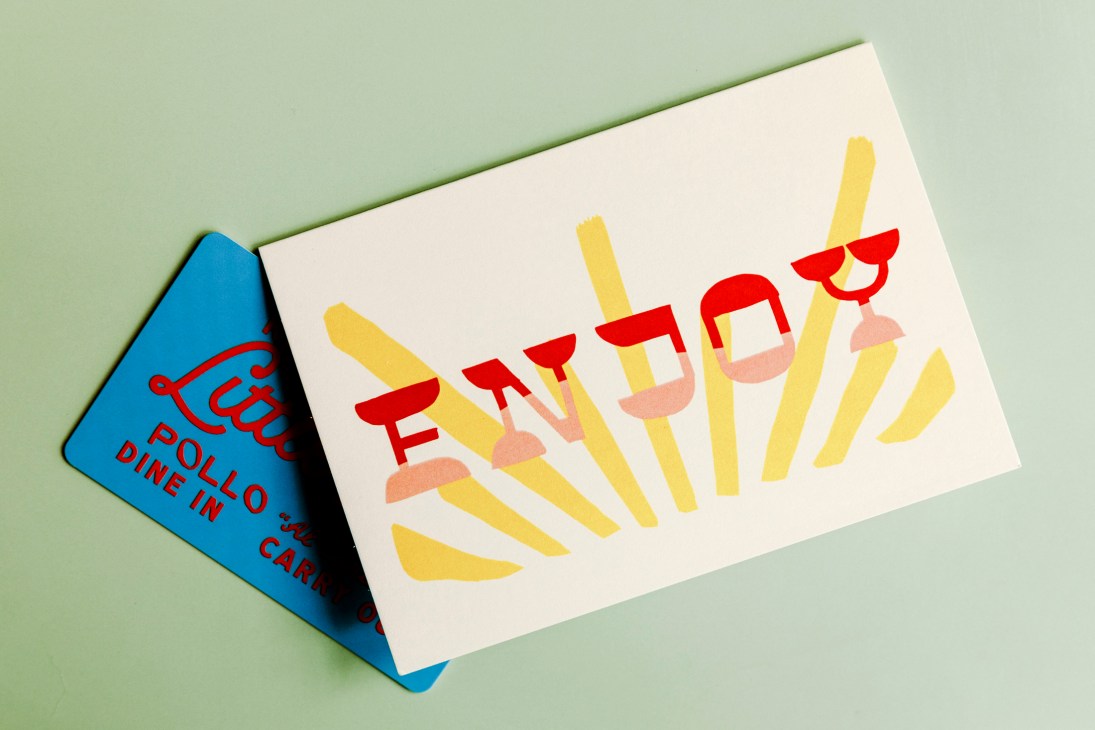Two business cards displayed at an angle, one blue card partially visible underneath a white card with red lettering