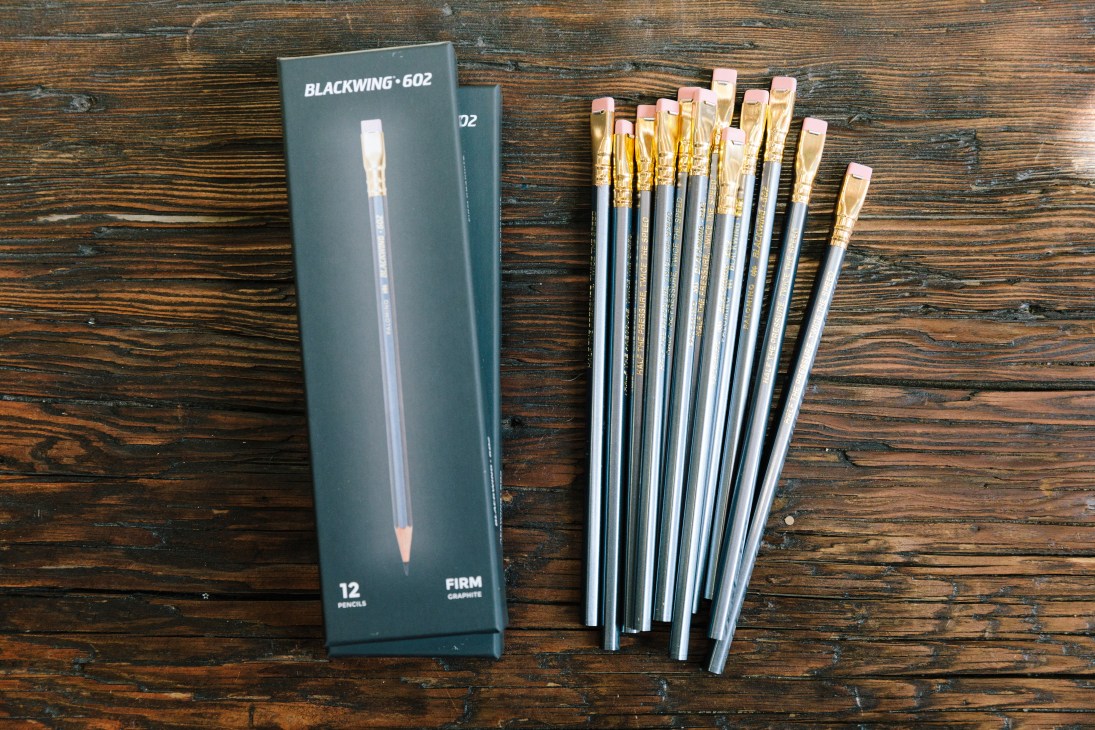 Blackwing 602 pencil box and individual pencils with flat ferrules displayed on wooden surface.