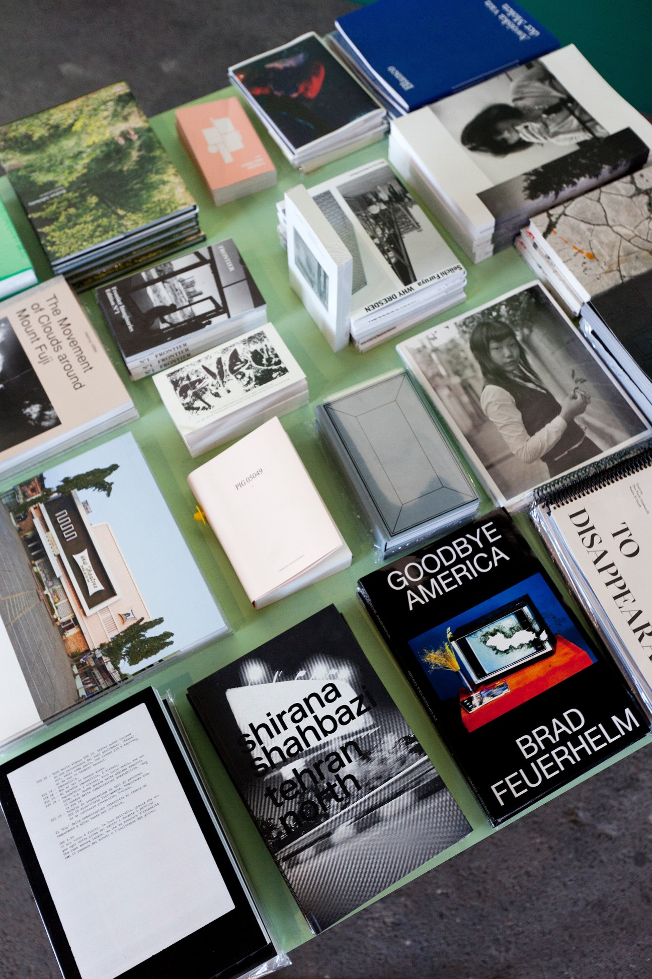 Various photography books and publications scattered on a green surface including works by Brad Feuerhelm