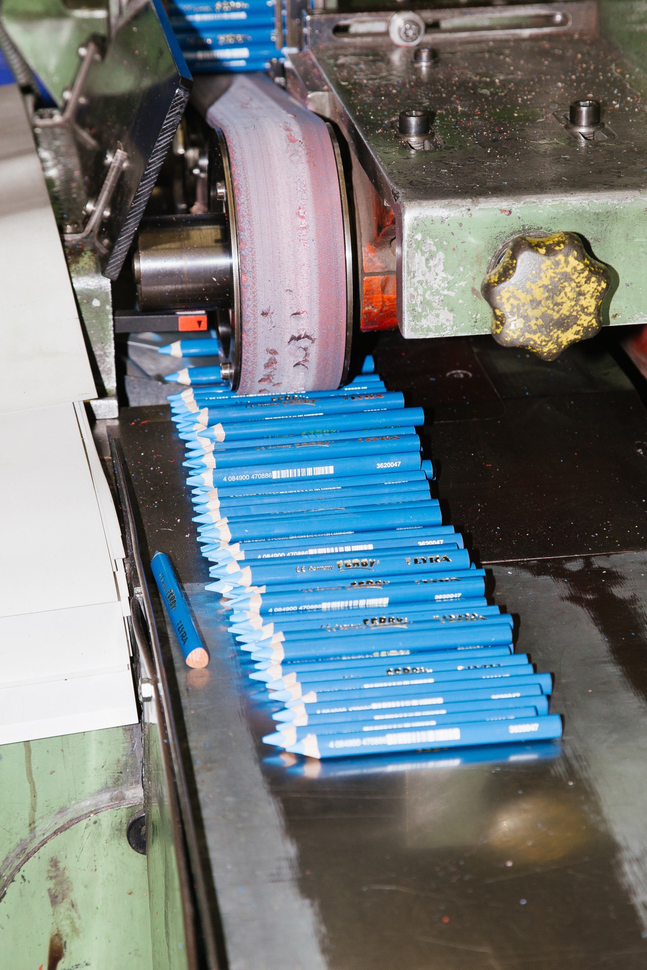 Blue pencils being sharpened by an automated machine at a pencil factory.