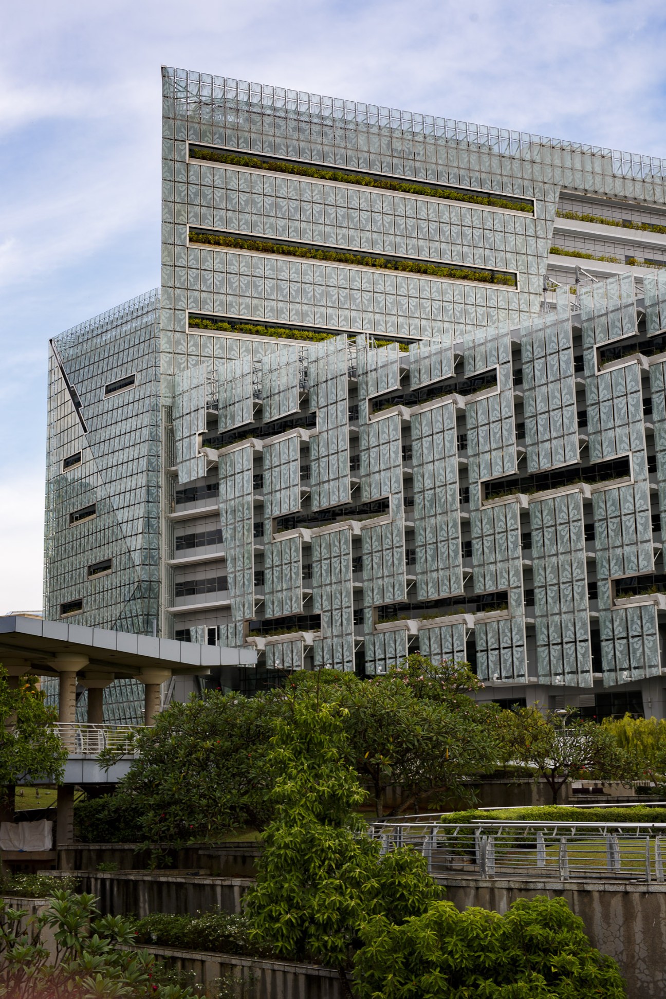 Modern glass and steel government building with green vegetation strips in Putrajaya, Malaysia's federal capital.