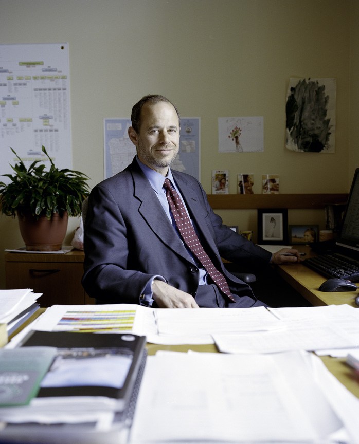 Ed Reiskin, director of public works, sits at his desk in an office with plants and artwork on the walls.