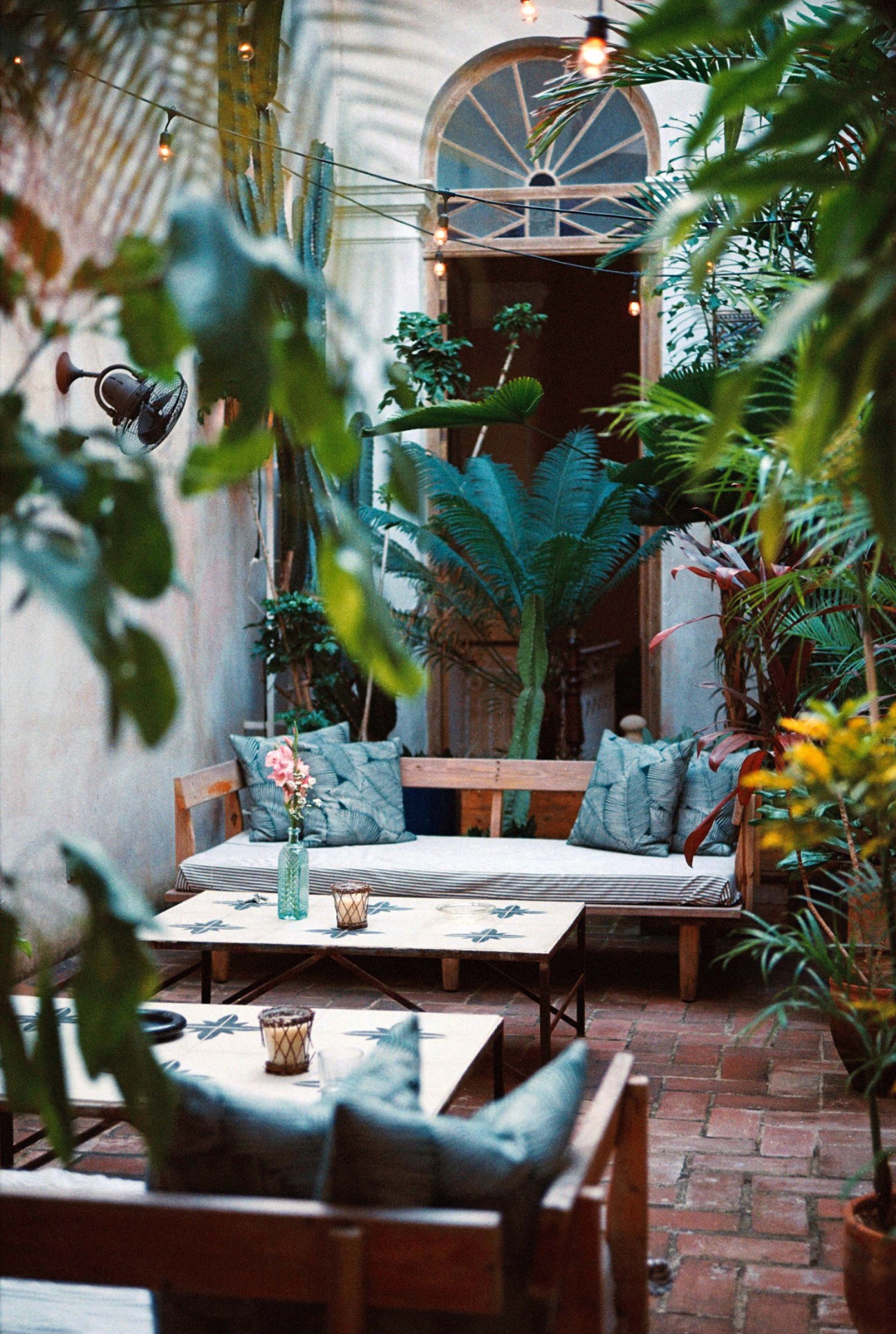 Tropical courtyard seating area with wooden furniture, plants, and string lights at Gardens hotel in Havana