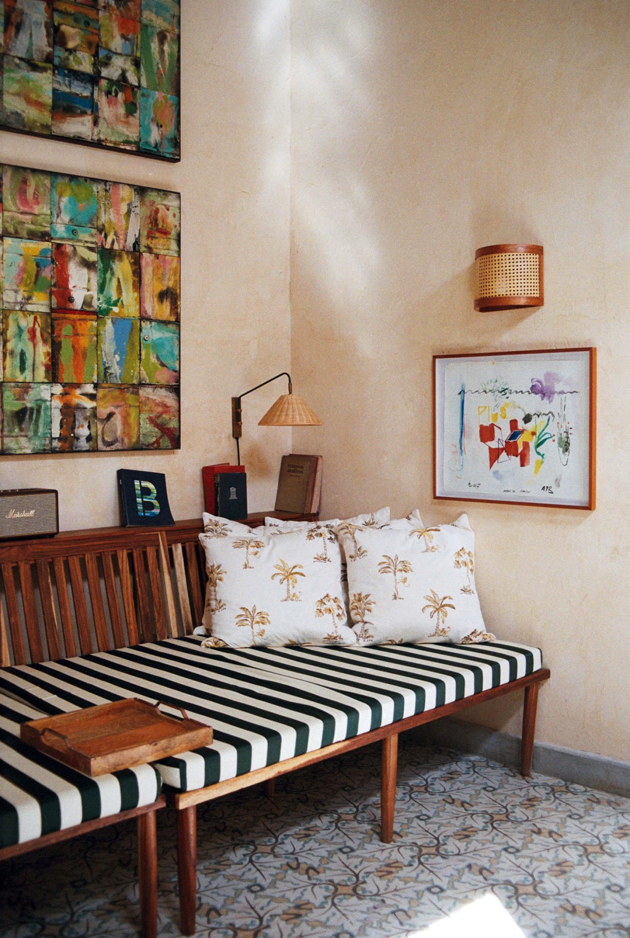 Reading room at Gardens hotel in Havana with striped daybed, palm tree pillows, and colorful artwork