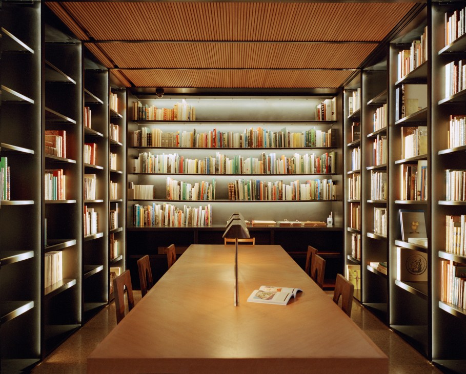 Oak-panelled reference library with illuminated bookshelves lining both sides of a wooden study table in the Marrakech Yves Saint Laurent Museum.