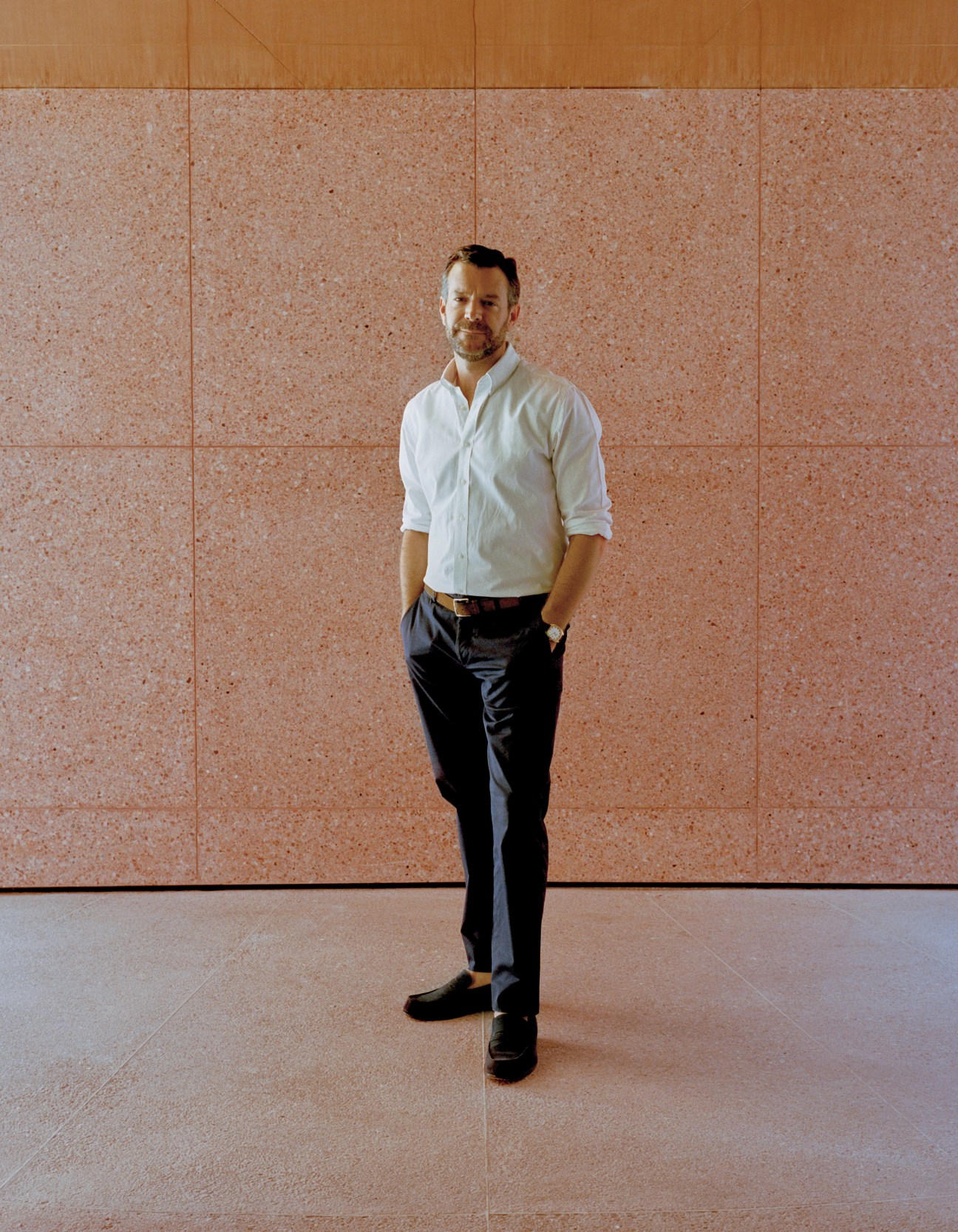 Curator Björn Dahlström stands against a rose-granite wall at the Marrakech Yves Saint Laurent museum.