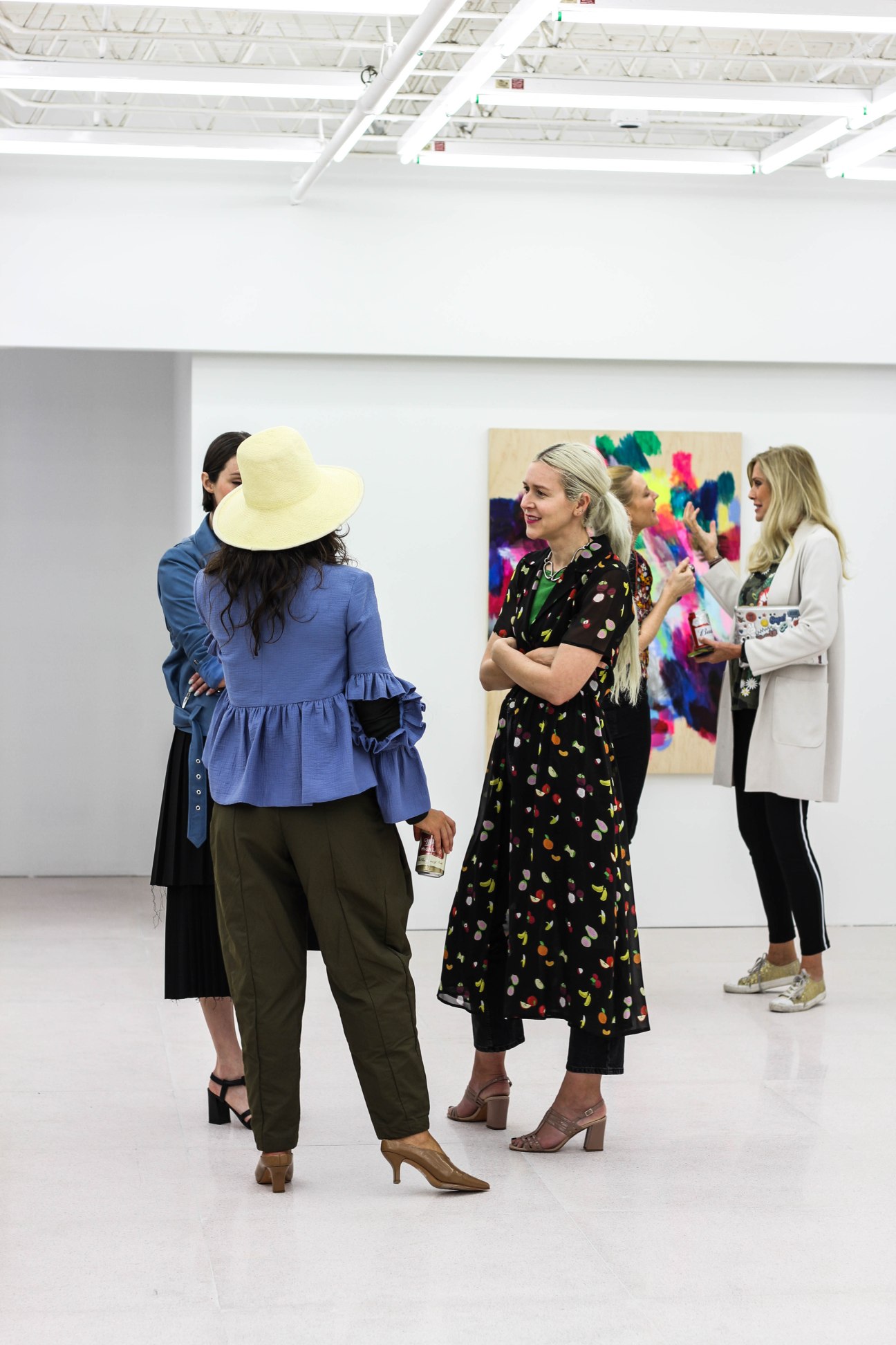 Visitors viewing contemporary artworks displayed on gallery walls in a white exhibition space.