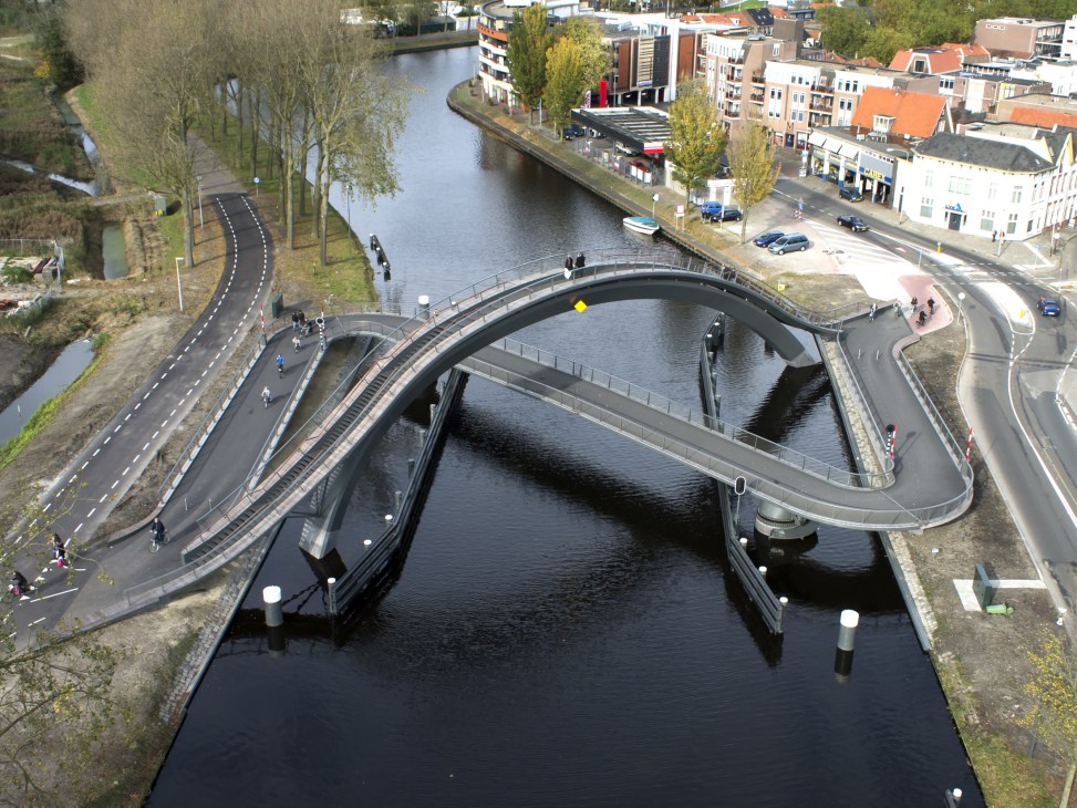 Aerial view of the Melkwegbridge in Purmerend showing its distinctive arching design spanning a canal with surrounding town buildings.