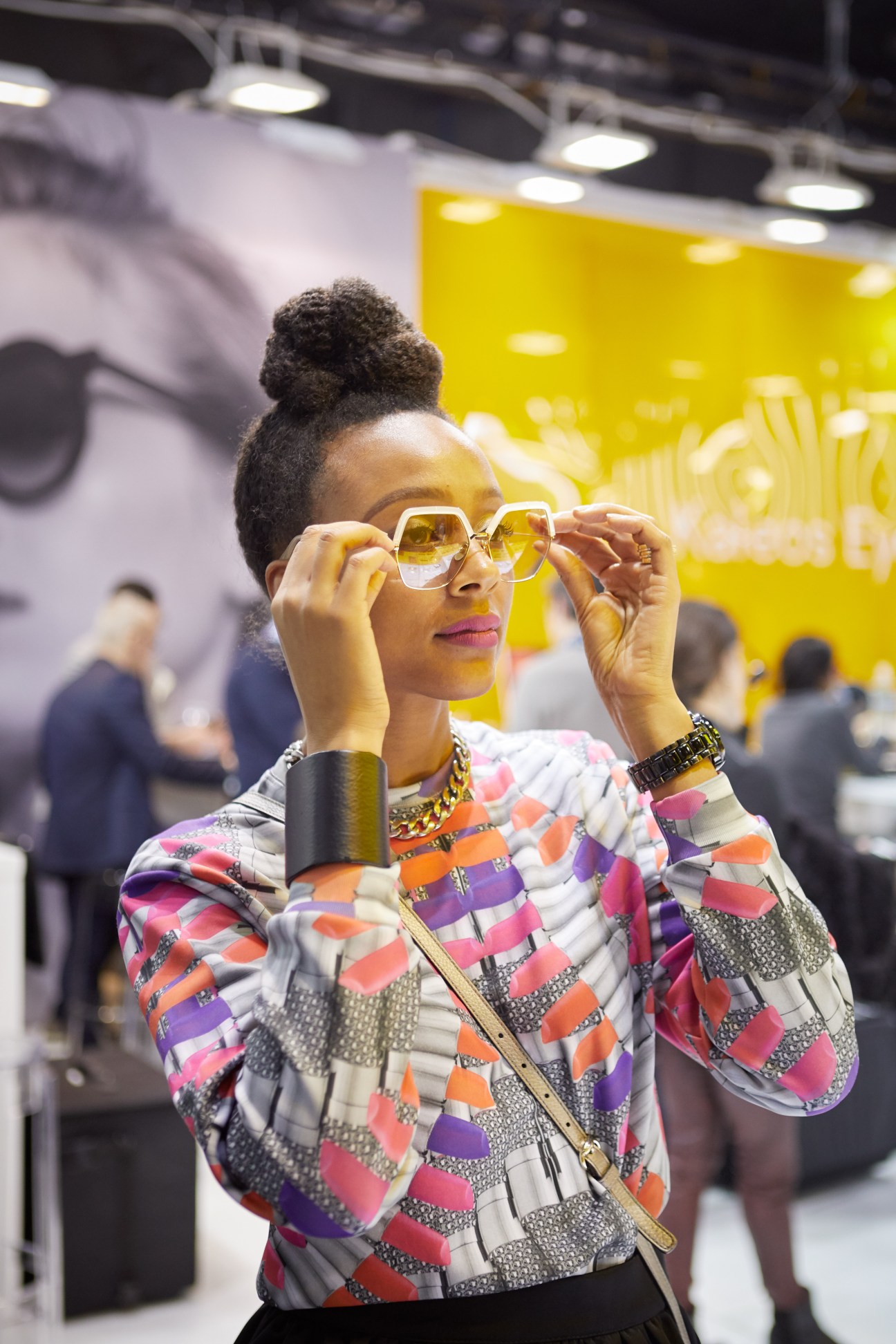 Woman trying on yellow-tinted sunglasses at Mido eyewear trade show in Milan.