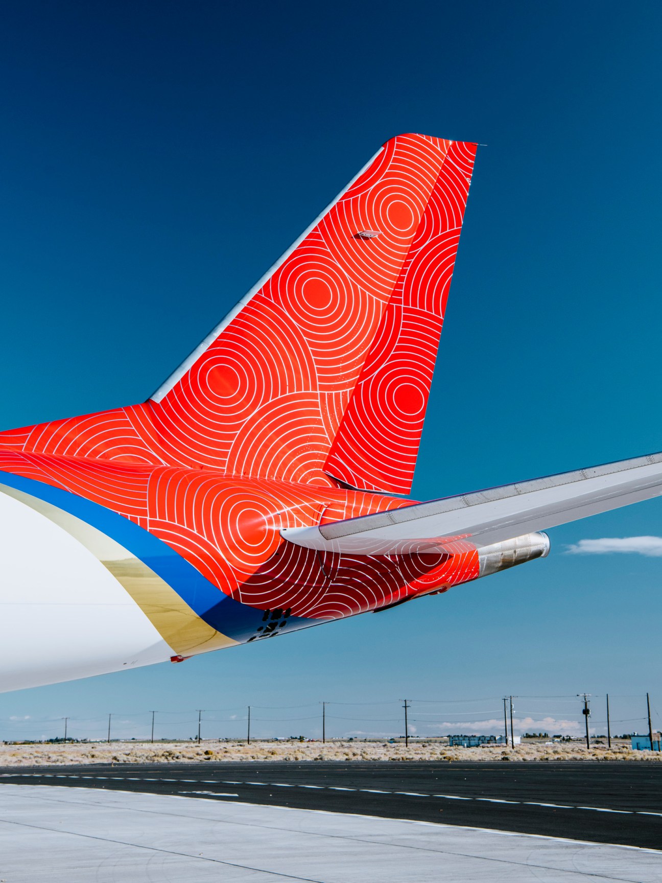 SpaceJet M90 aircraft tail displaying distinctive red circular pattern livery against clear blue sky