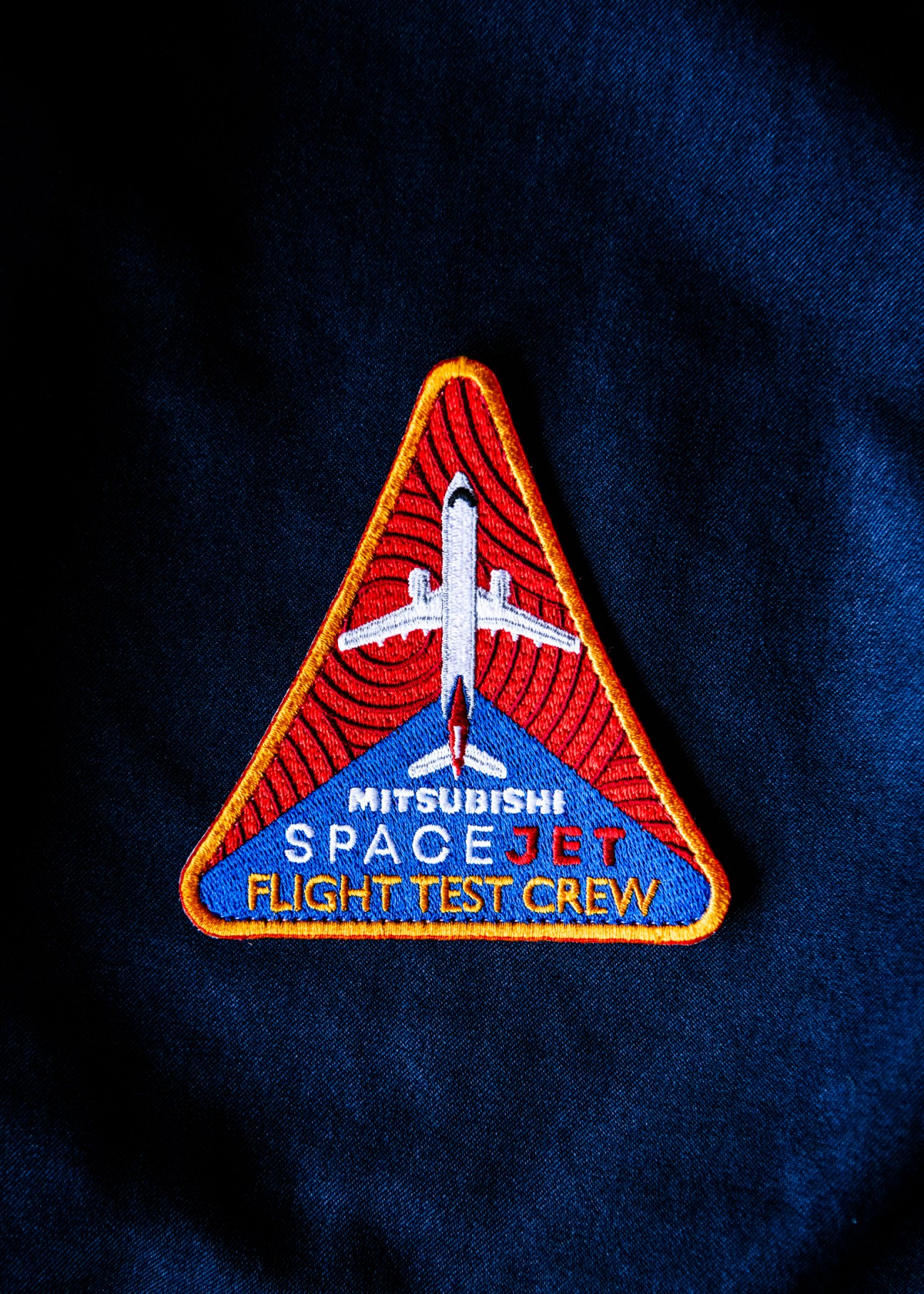 Triangular embroidered patch showing Mitsubishi SpaceJet Flight Test Crew insignia with aircraft silhouette