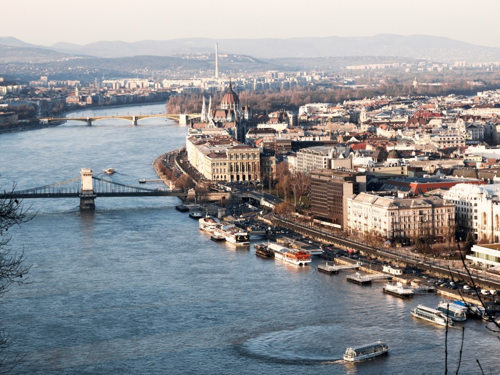 Budapest cityscape showing the Danube River, Parliament Building, Chain Bridge, and surrounding architecture.