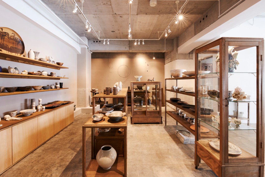 Interior of Mizusai Tokyo shop displaying ceramics and crafts on wooden shelves and display cases.