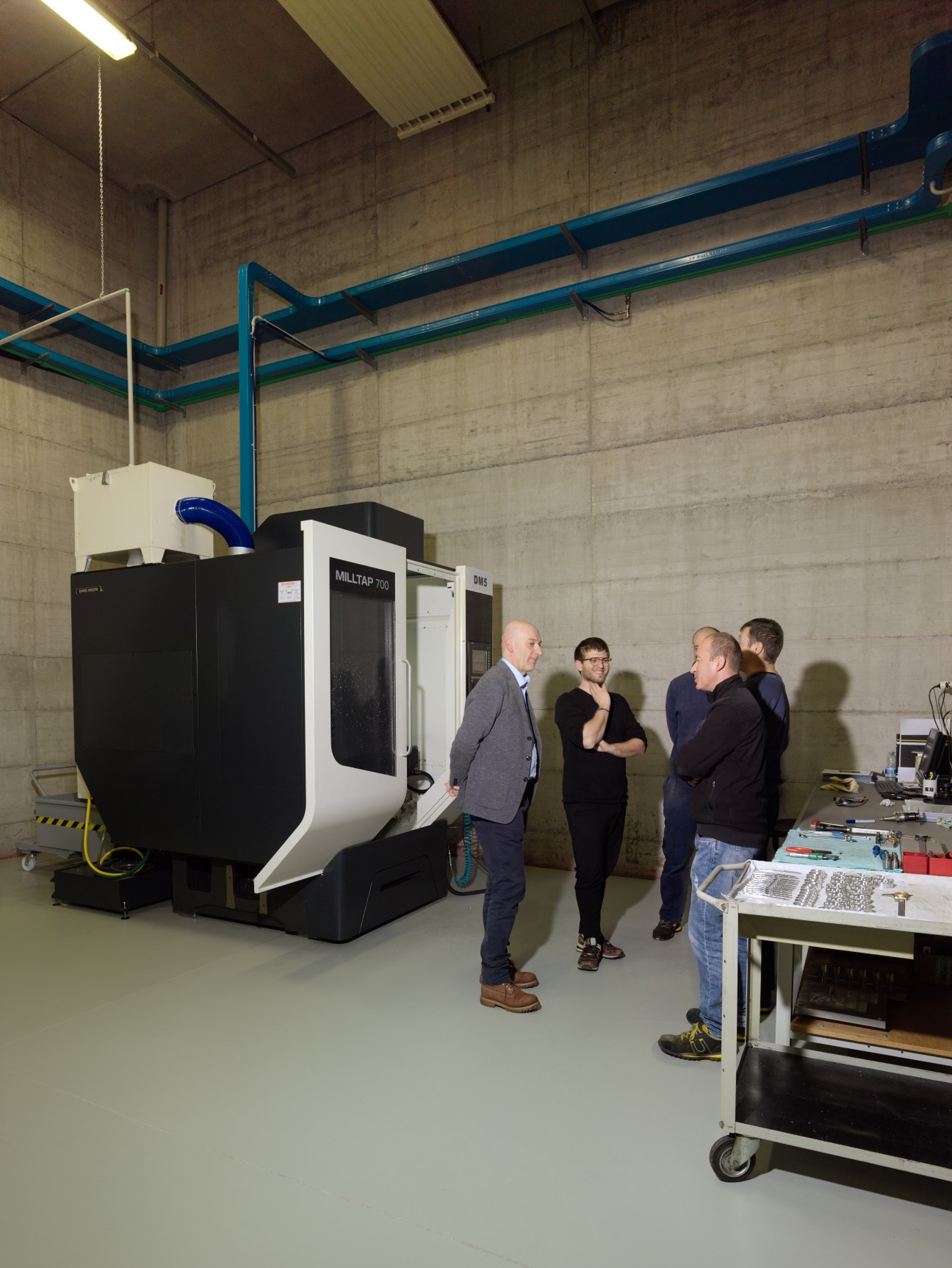 Staff members in Gibellini's studio in Sassuolo stand near industrial machinery and equipment.