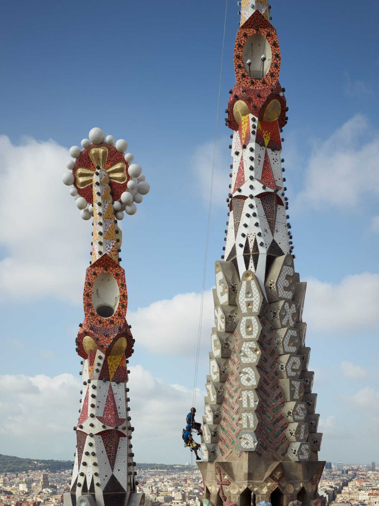 A worker carefully cleans stone sculptures and architectural details on the Sagrada Família basilica's facade.