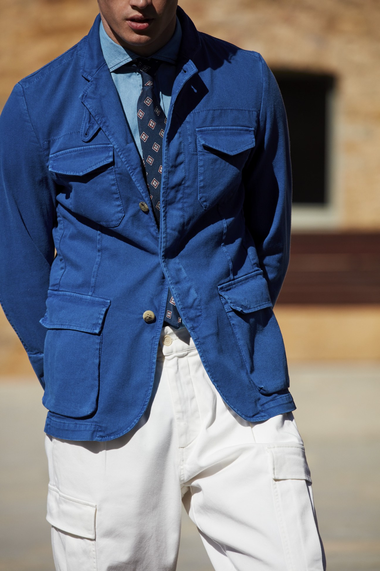 Male model wearing a blue Jacob Cohën jacket, Drake's shirt and tie, and Barena Venezia white trousers.
