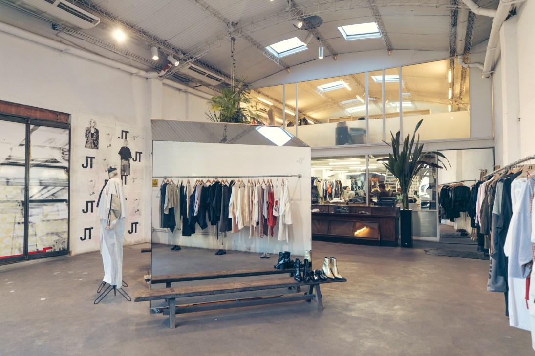 Interior of JT shop in Palermo displaying womenswear on racks and mannequins in industrial warehouse space.