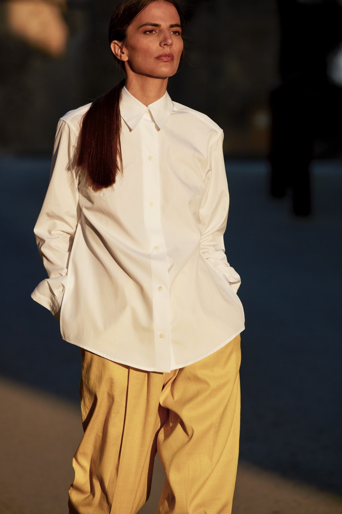 Woman wearing a cream button-up shirt by Gabriela Coll and mustard yellow trousers by Barena Venezia.