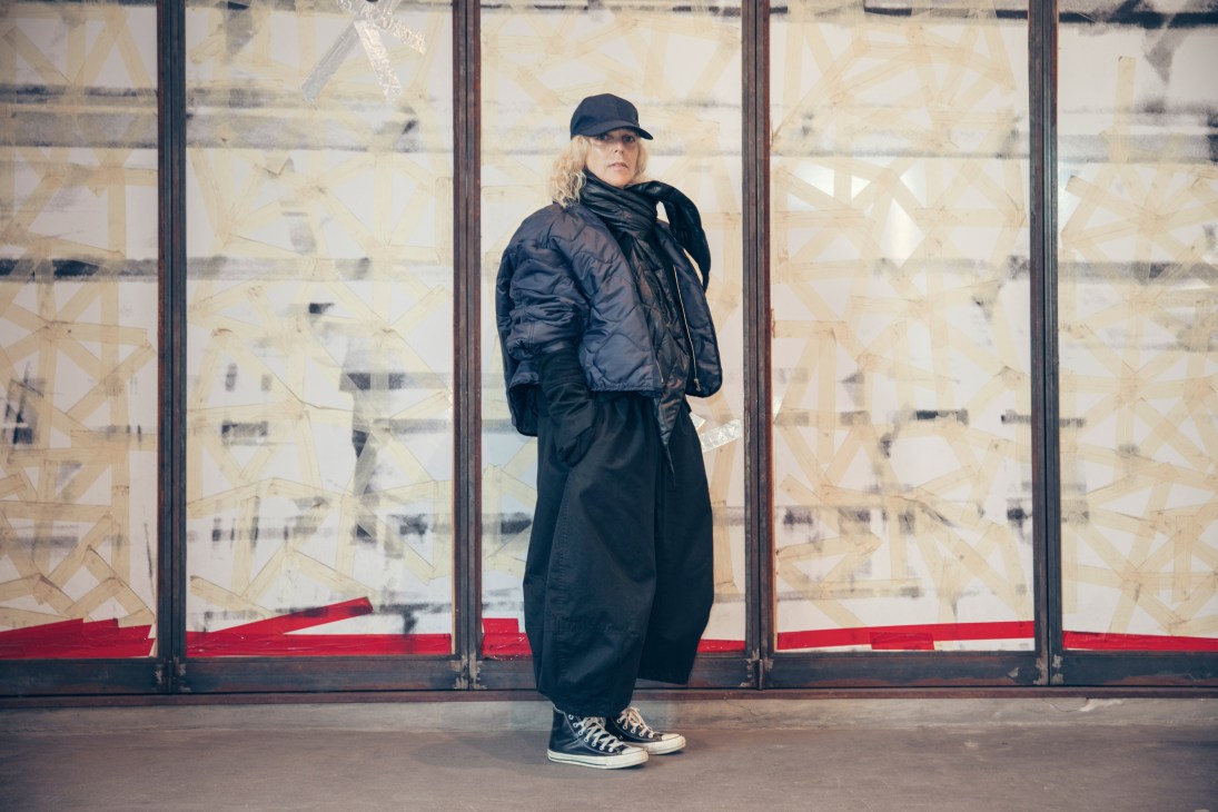 Woman wearing a black puffer jacket and black pants standing in front of a storefront window