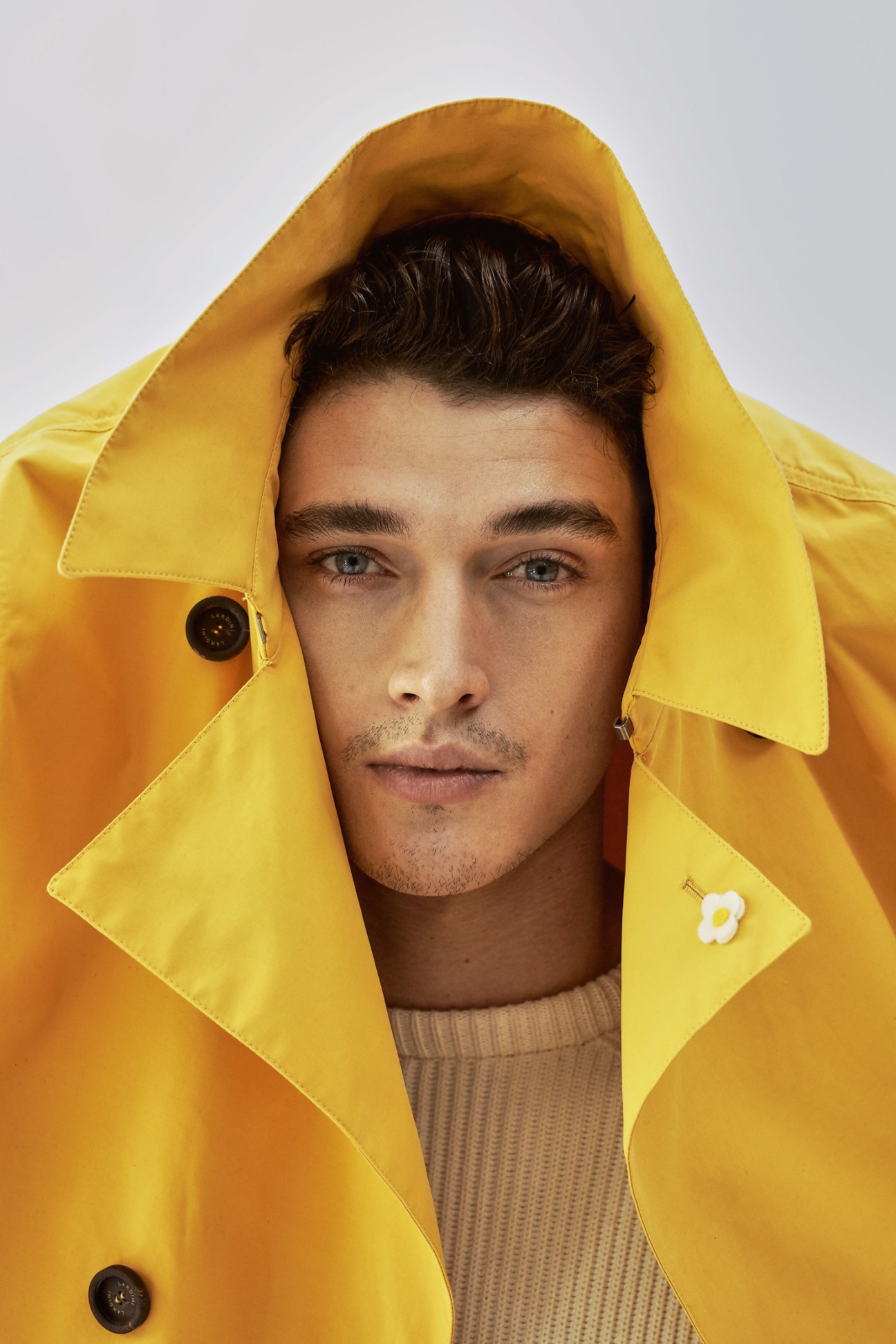 Man wearing a bright yellow jacket by Lardini and De Bonne Facture jumper with hood up.