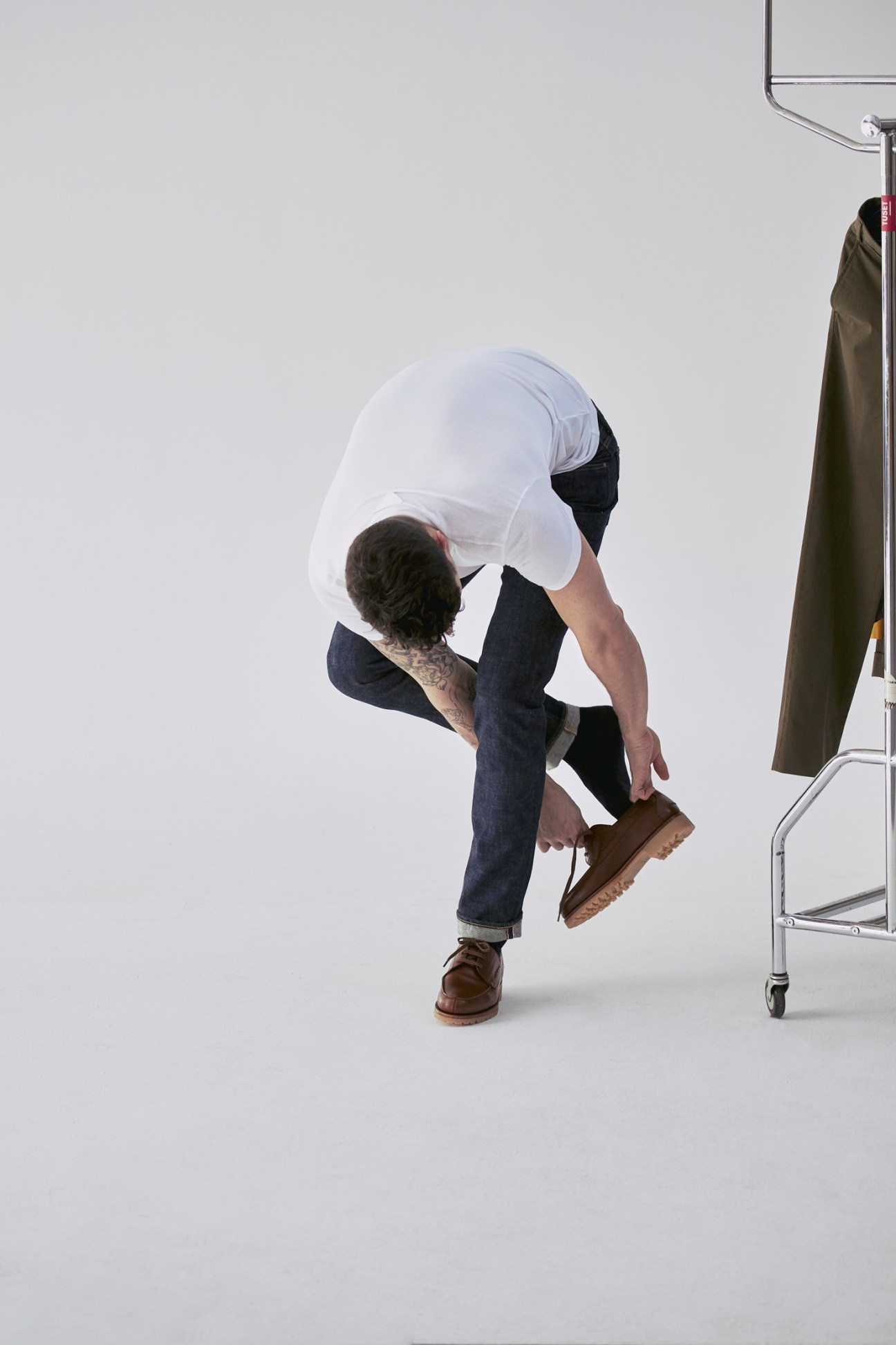 Model wearing The Workers Club jeans, Falke socks, and JM Weston shoes in studio setting.