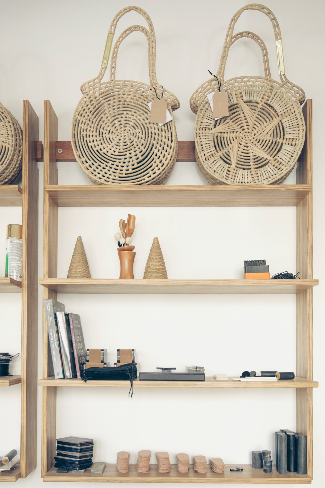Woven palm leaf canasto basket bags displayed on wooden shelving with accessories by Josefina Romero.