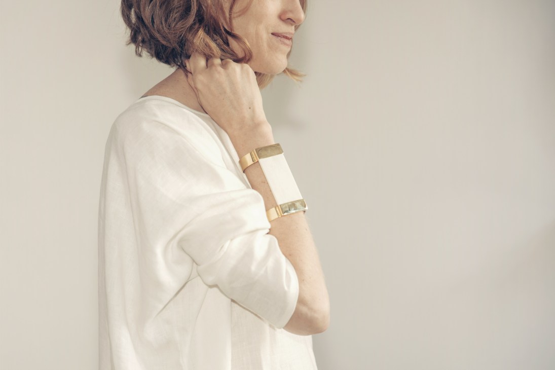 Woman wearing a white dress and gold-toned metal bracelet designed by Romero.