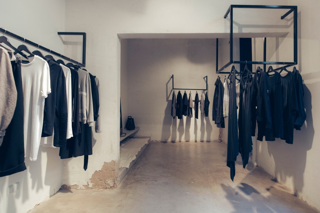 Interior of Tupã multibrand concept store with minimal clothing displays on metal racks.