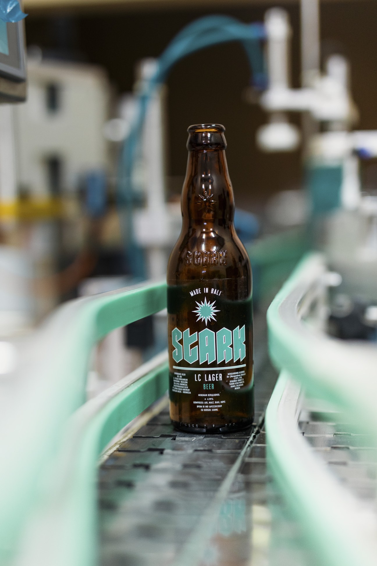 Bottles of Stark beer displayed with brewery equipment in background