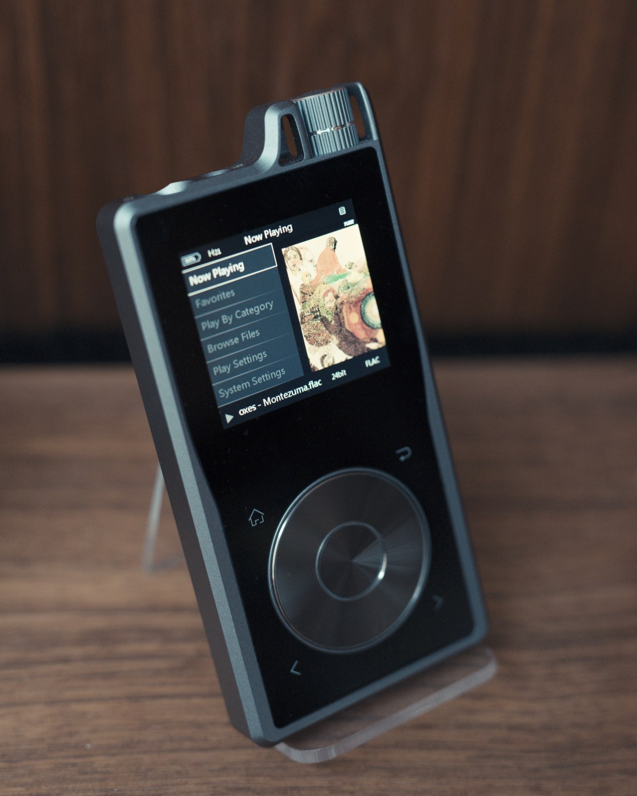Questyle QP1R high-resolution digital audio player displaying menu on screen against brown backdrop.