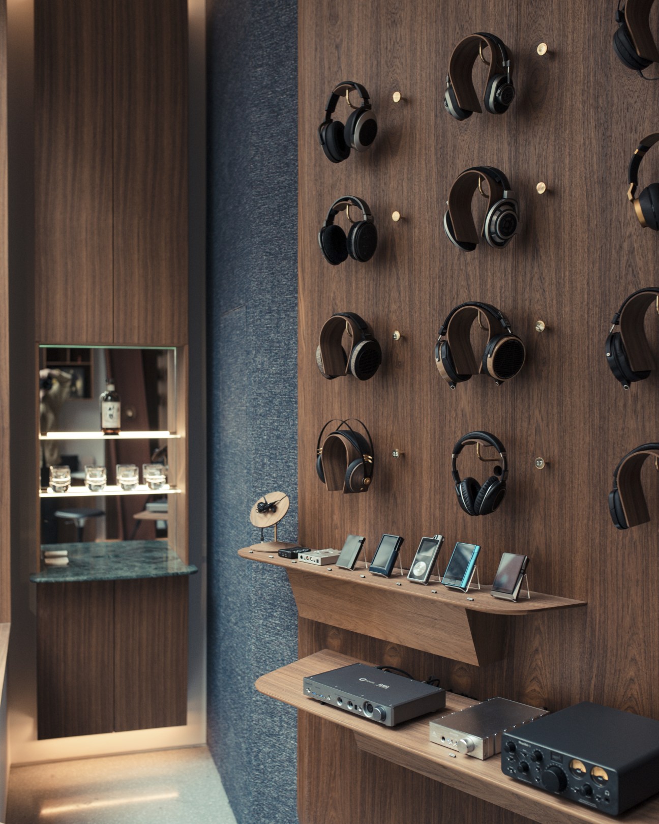 Headphones displayed on wooden wall with digital audio players on shelf below and audio equipment in Spiritland's headphone bar.