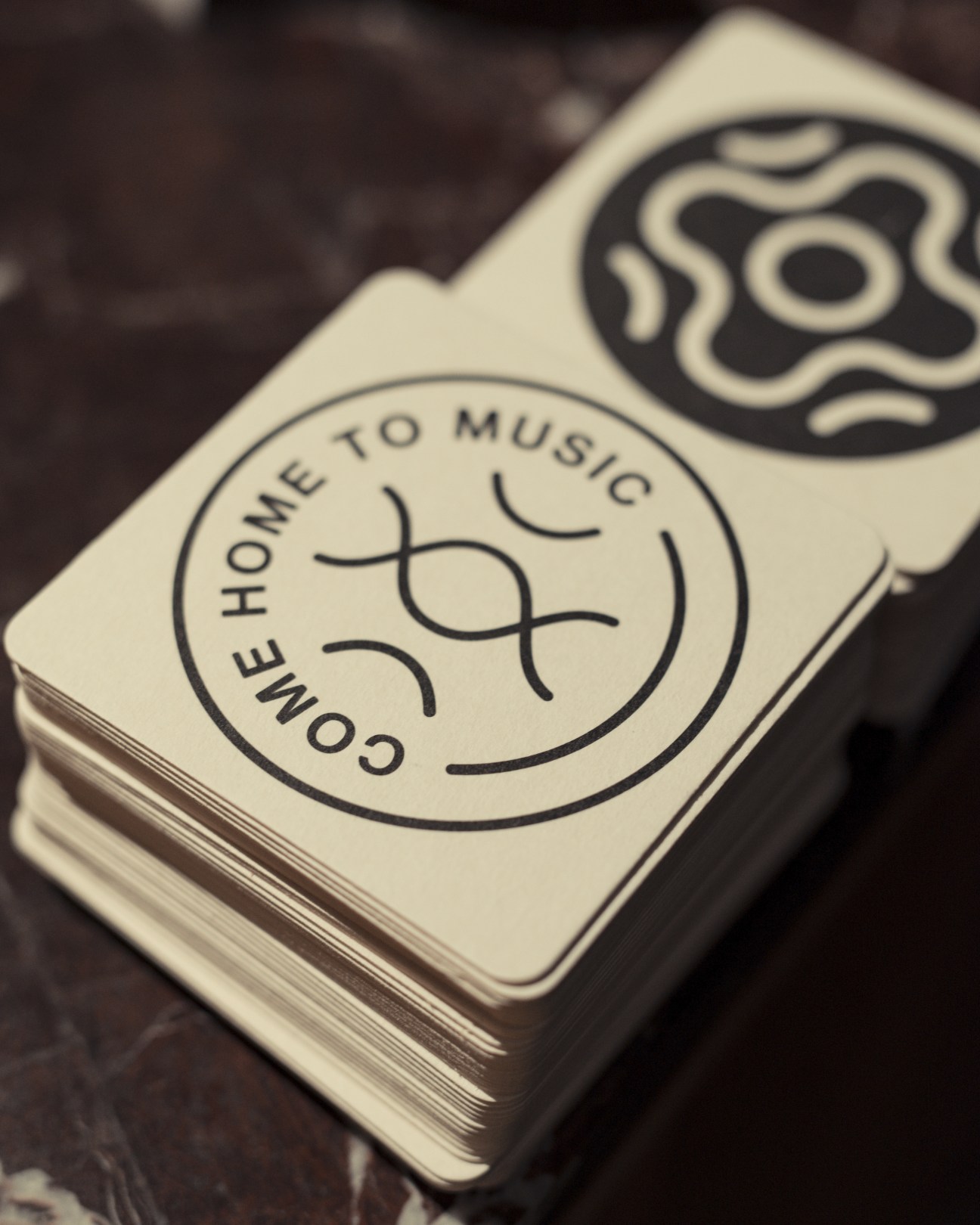 Close-up of Spiritland branding showing a circular logo with text "Come home to music" on cream-colored material.