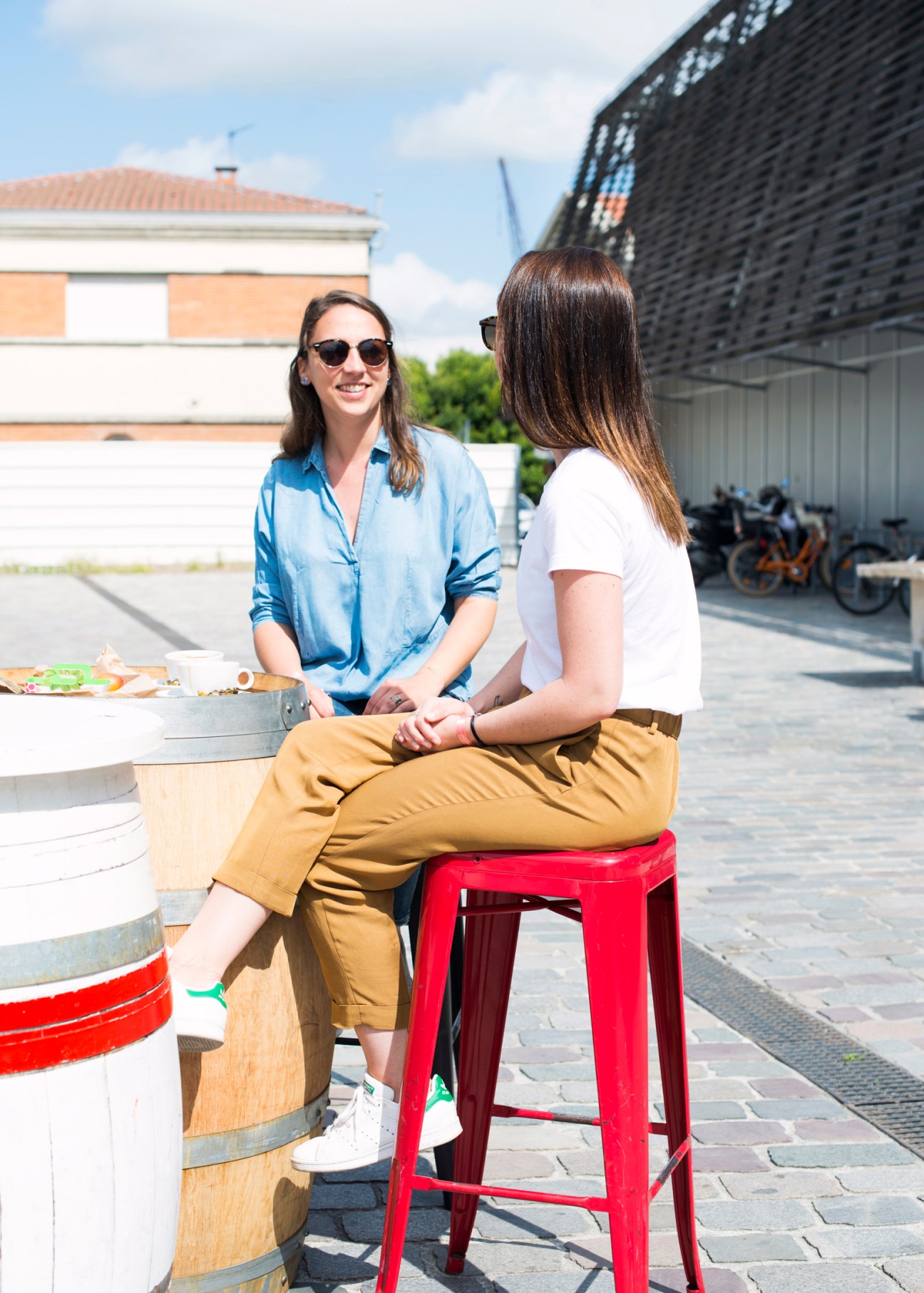 Two women sitting at a high table with food in an outdoor courtyard setting in Bordeaux.