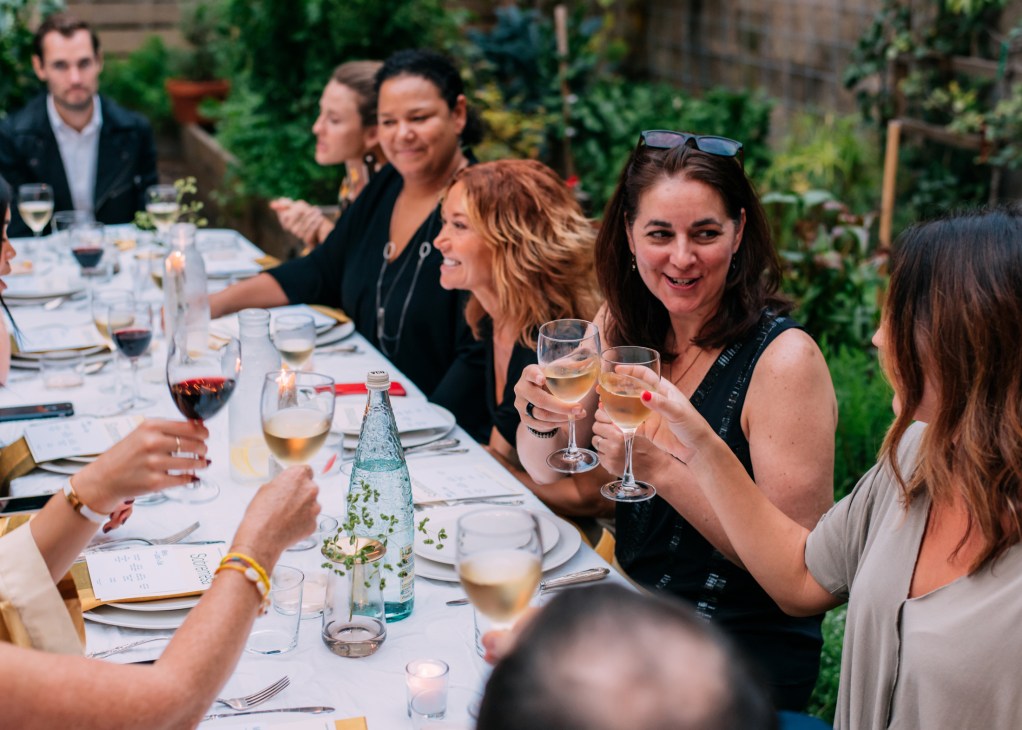 Guests raising glasses for a toast at Sobremesa dinner